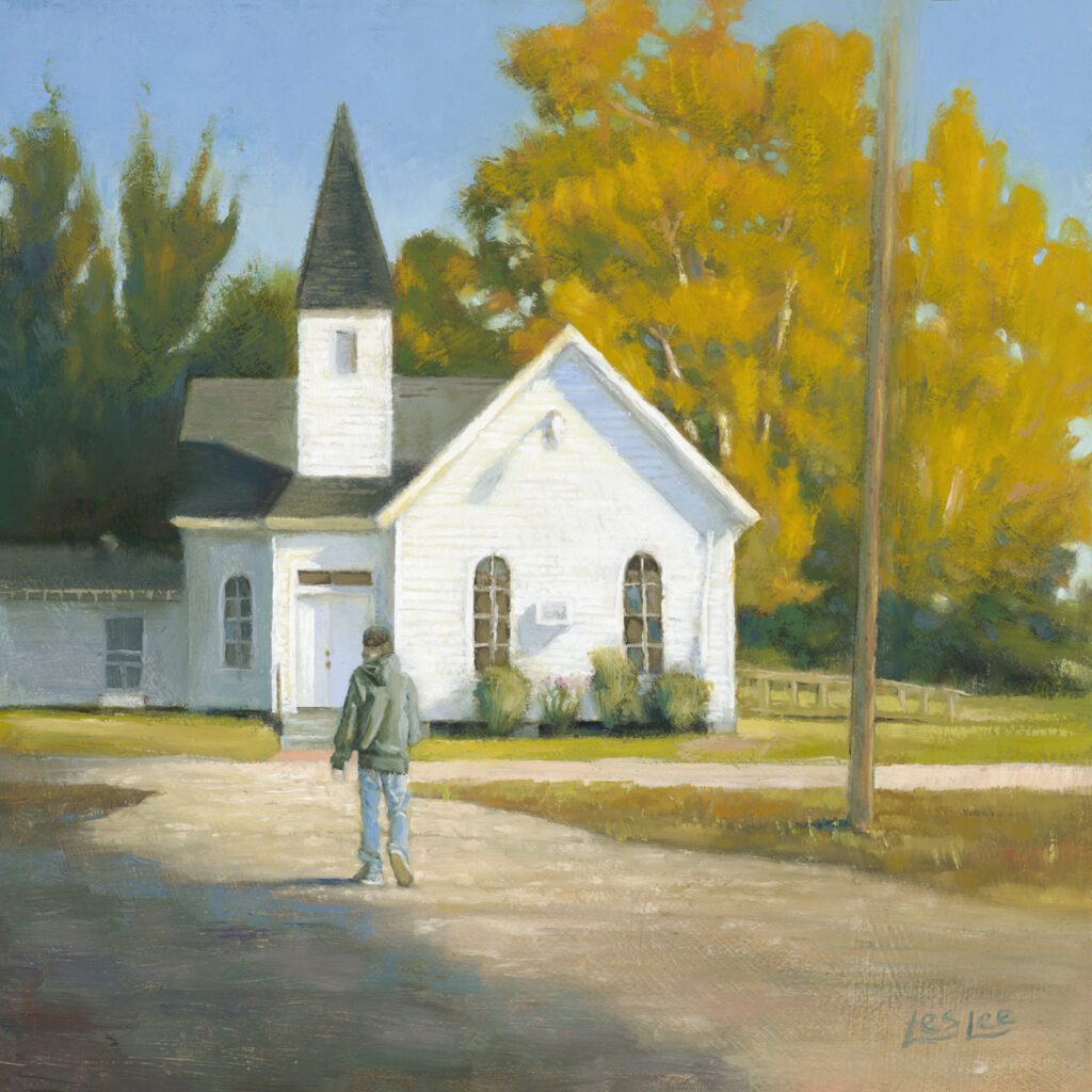 An white painted country church in fall with a young man walking toward it.
